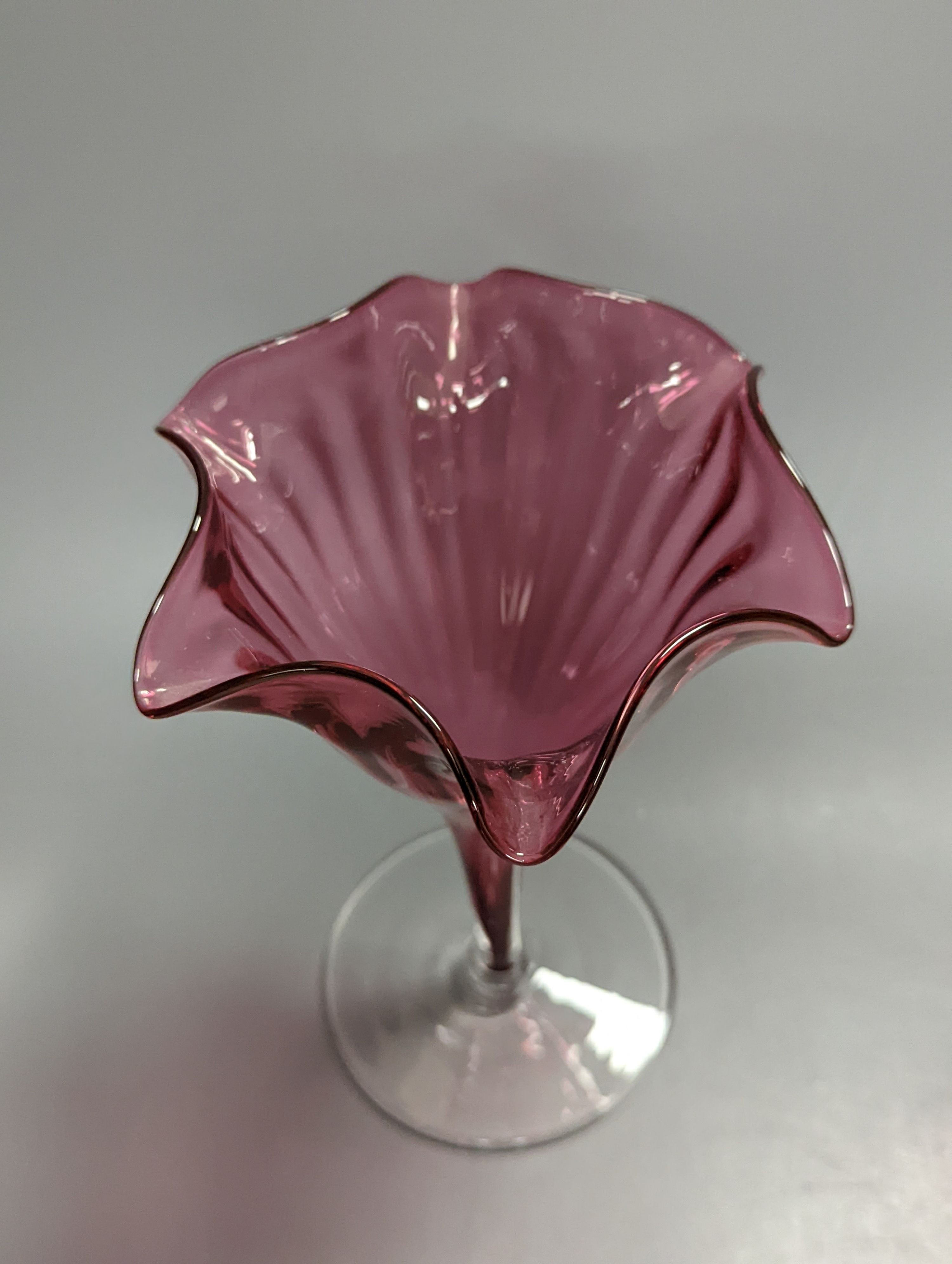 A pair of late Victorian cranberry glass frill vases, height 23cm, and a similar tapering jug
